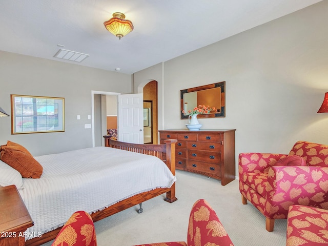 bedroom with arched walkways, carpet flooring, and visible vents