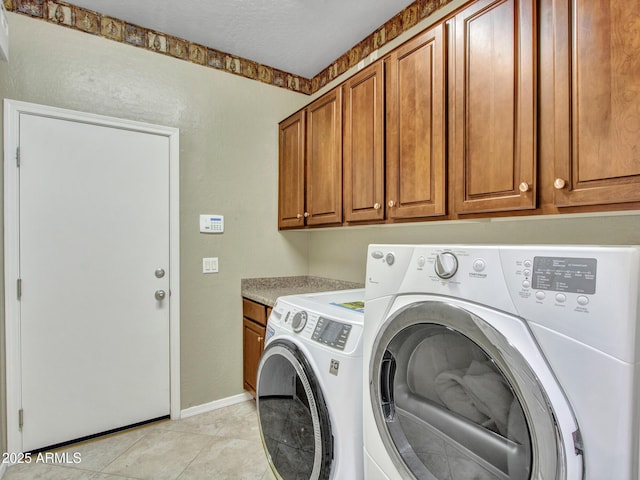 laundry room featuring baseboards, separate washer and dryer, light tile patterned flooring, and cabinet space