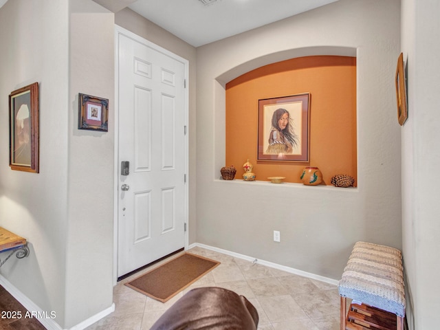 foyer with arched walkways, baseboards, and light tile patterned floors