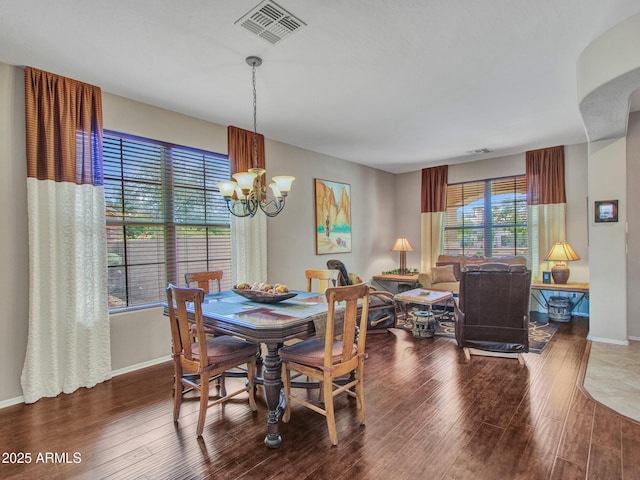dining area with a chandelier, baseboards, visible vents, and wood finished floors