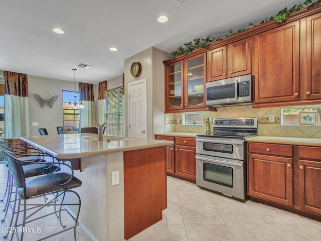 kitchen featuring a breakfast bar area, a sink, backsplash, appliances with stainless steel finishes, and recessed lighting