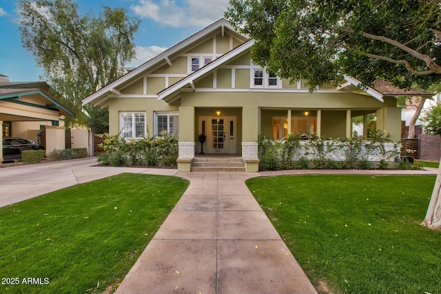 view of front of home featuring brick siding, covered porch, stucco siding, and a front lawn