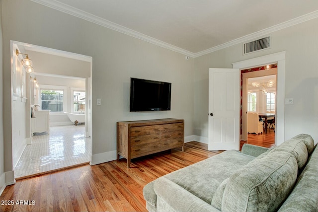 living room with light wood-style floors, visible vents, and ornamental molding