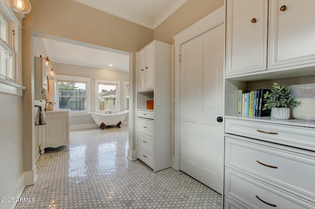 interior space featuring crown molding, baseboards, and a sink