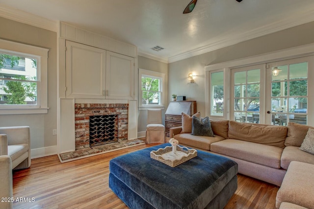 living room with visible vents, a healthy amount of sunlight, a fireplace, and light wood-style flooring