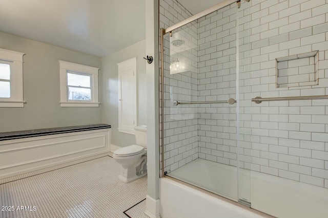 full bath with tile patterned flooring, toilet, and bath / shower combo with glass door