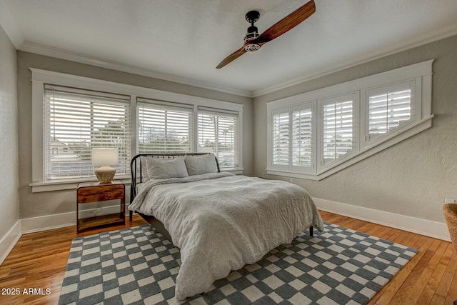 bedroom with crown molding, wood finished floors, and baseboards