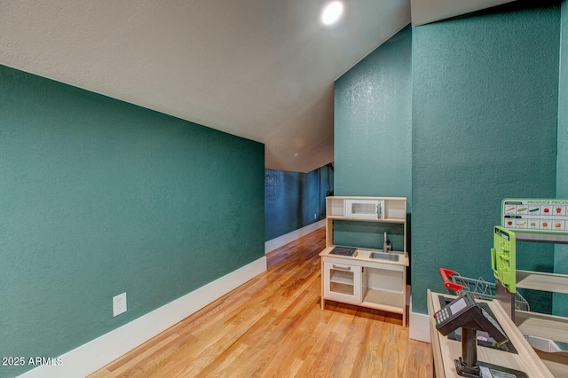 interior space featuring baseboards, wood finished floors, and a textured wall