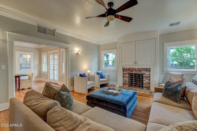 living room with crown molding, visible vents, and light wood-type flooring