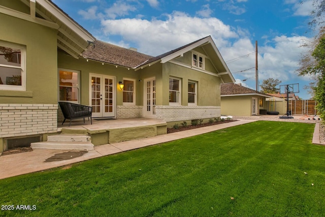 rear view of property with brick siding, fence, a lawn, french doors, and a patio area