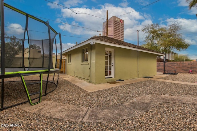 view of home's exterior with a fenced backyard, stucco siding, and a trampoline