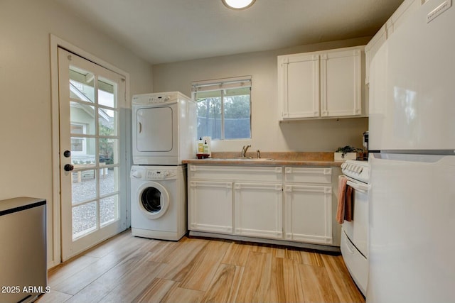 laundry area with light wood finished floors, laundry area, stacked washer / drying machine, and a sink