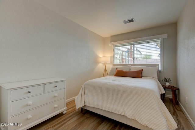 bedroom featuring dark wood-style floors, visible vents, and baseboards