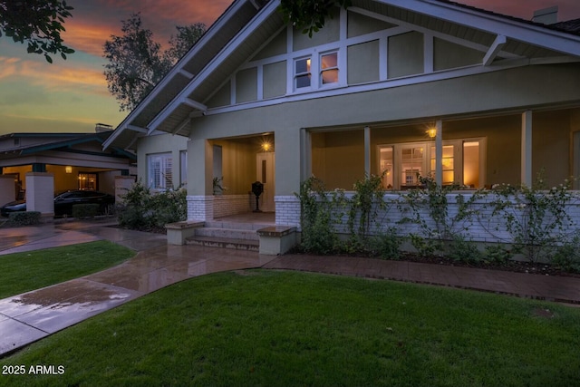 view of front of property with stucco siding, brick siding, and a front yard