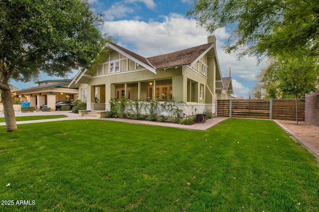 view of front of house featuring stucco siding, a chimney, a front yard, and fence