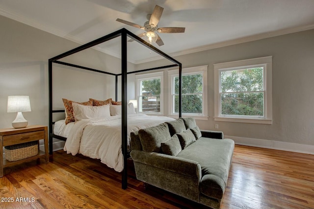 bedroom featuring a ceiling fan, crown molding, wood finished floors, and baseboards