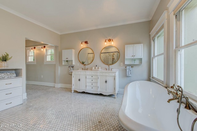 full bath with baseboards, double vanity, a freestanding tub, a sink, and crown molding