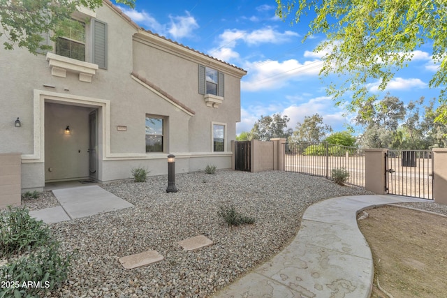 view of side of property with fence, a gate, and stucco siding