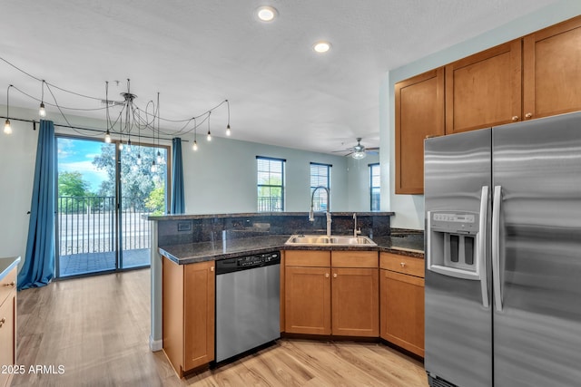 kitchen with a sink, a peninsula, brown cabinets, and stainless steel appliances
