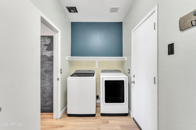 laundry room featuring separate washer and dryer, laundry area, wood finished floors, and visible vents
