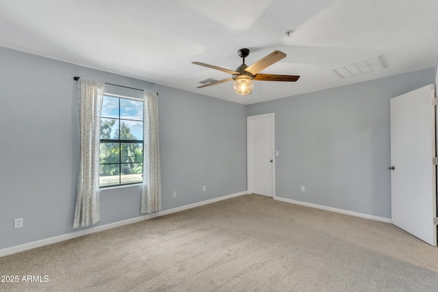 carpeted empty room with baseboards, a ceiling fan, and visible vents