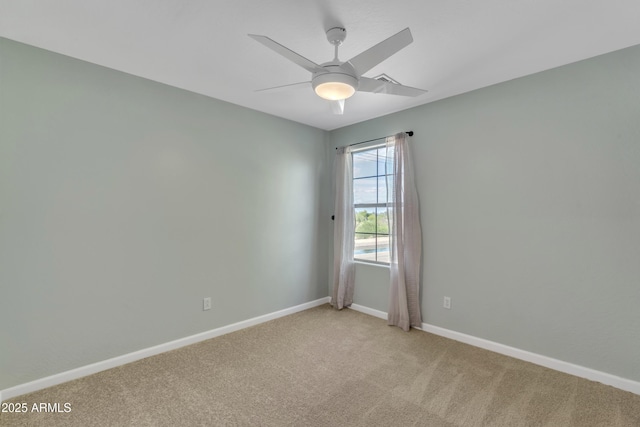 spare room featuring light colored carpet, baseboards, and ceiling fan