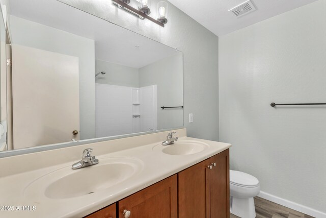 bathroom featuring a sink, toilet, wood finished floors, and visible vents