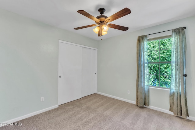 unfurnished bedroom featuring a ceiling fan, baseboards, carpet, and a closet