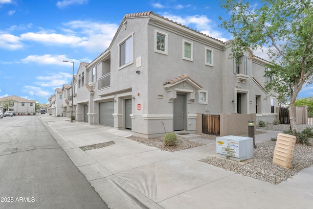 view of front of property with a garage, a residential view, a tile roof, and stucco siding