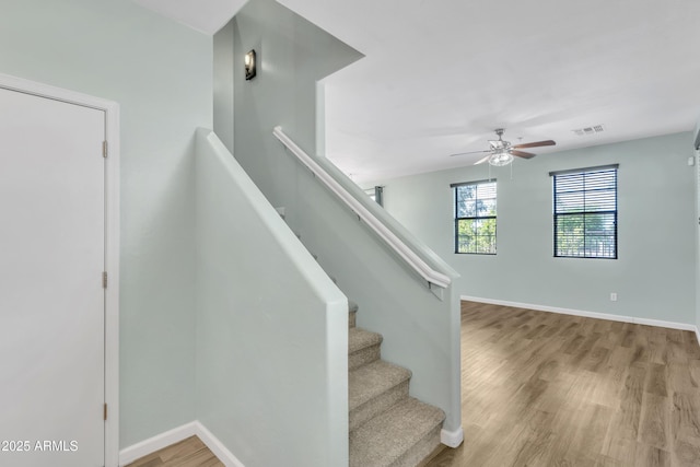 staircase featuring baseboards, ceiling fan, wood finished floors, and visible vents