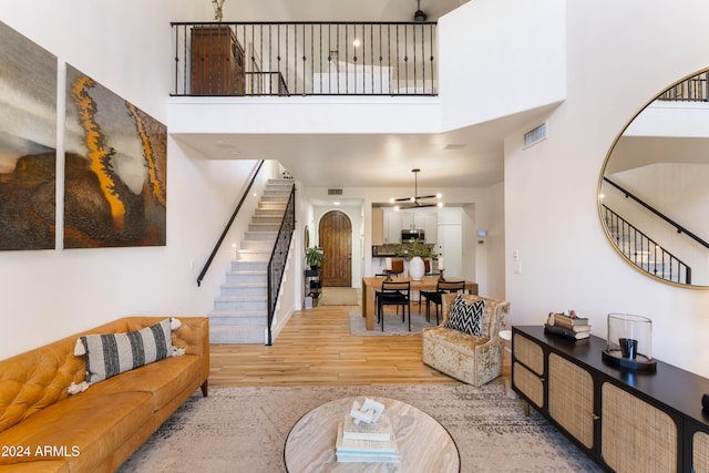 living room with a high ceiling, light wood-type flooring, and a notable chandelier