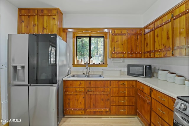 kitchen with light countertops, brown cabinets, appliances with stainless steel finishes, and a sink