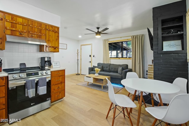 kitchen featuring a ceiling fan, under cabinet range hood, brown cabinets, and stainless steel electric range oven