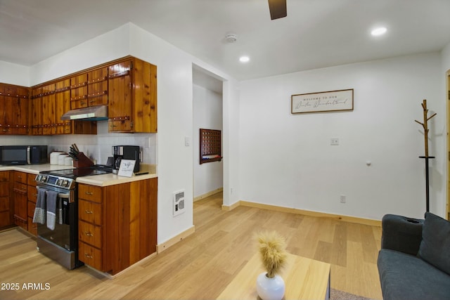 kitchen with black microwave, electric range oven, tasteful backsplash, under cabinet range hood, and visible vents