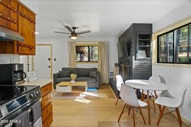 living room featuring ceiling fan, plenty of natural light, and light wood-style floors