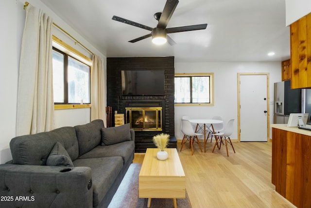 living room featuring a brick fireplace, recessed lighting, ceiling fan, and light wood-style floors