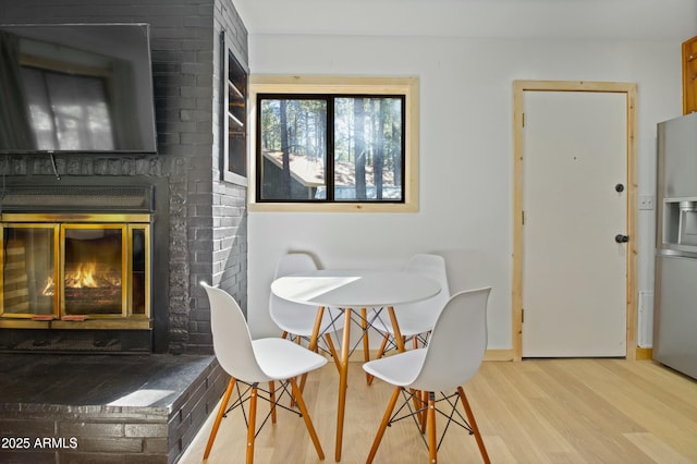 dining area featuring baseboards, a fireplace, and wood finished floors