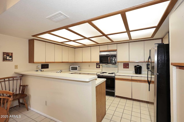 kitchen featuring light tile patterned flooring, stainless steel refrigerator, kitchen peninsula, cream cabinets, and electric stove