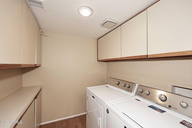 washroom featuring cabinets, separate washer and dryer, hardwood / wood-style floors, and a textured ceiling