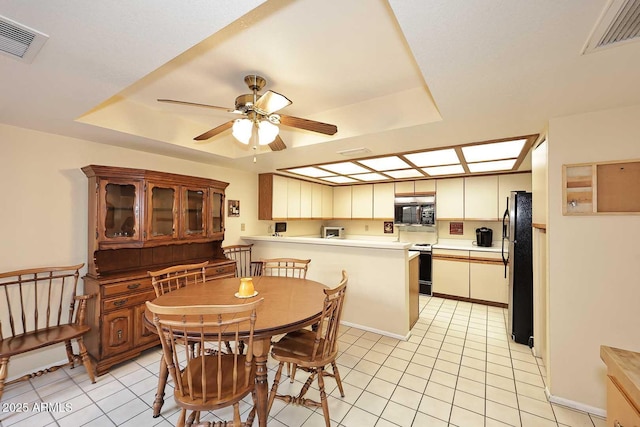 dining area featuring light tile patterned flooring, ceiling fan, and a raised ceiling