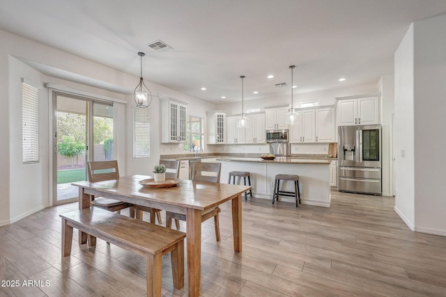 dining space featuring light wood-style floors, baseboards, and visible vents