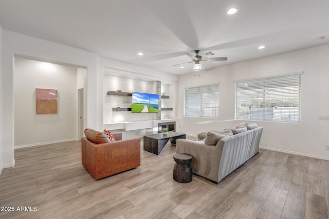 living area featuring baseboards, ceiling fan, light wood-style flooring, and visible vents