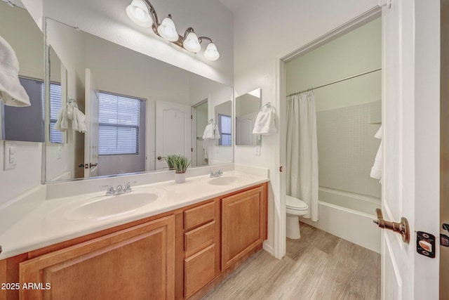full bathroom featuring double vanity, toilet, a sink, and wood finished floors