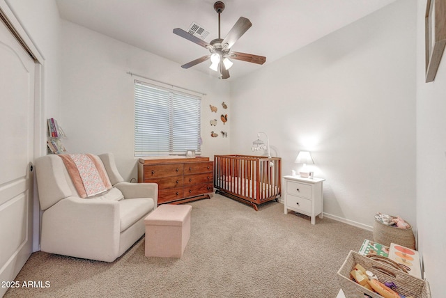 bedroom with a ceiling fan, visible vents, a nursery area, a closet, and light carpet