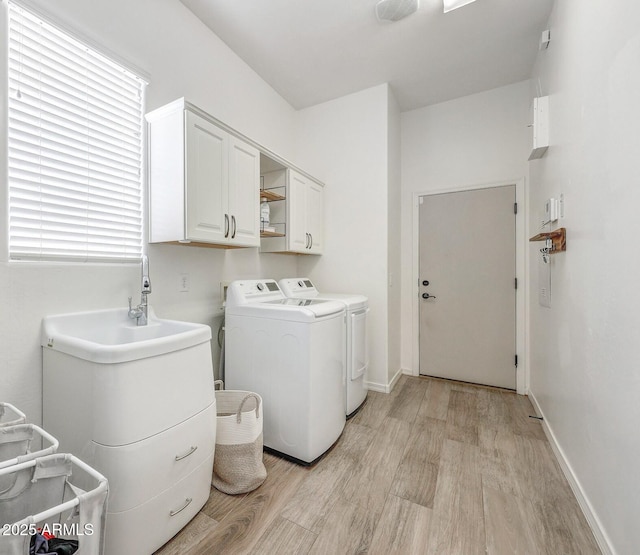 laundry area with light wood-style floors, separate washer and dryer, baseboards, and cabinet space