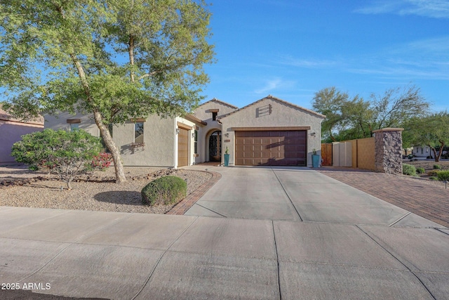view of front of home featuring fence, an attached garage, driveway, and stucco siding