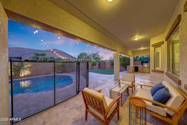 view of patio / terrace featuring a fenced backyard, a fenced in pool, an outdoor hangout area, and an outdoor kitchen