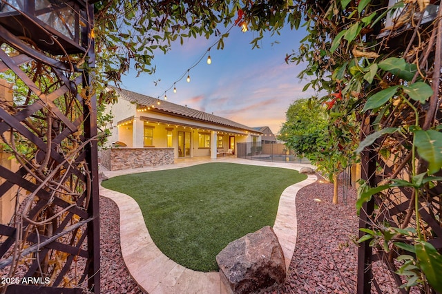 yard at dusk featuring a patio and a fenced backyard