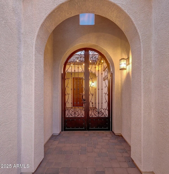 view of exterior entry featuring a gate and stucco siding