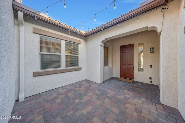 property entrance with a patio and stucco siding